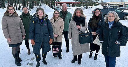 En grupp människor står utomhus på vintern och tittar in i kameran