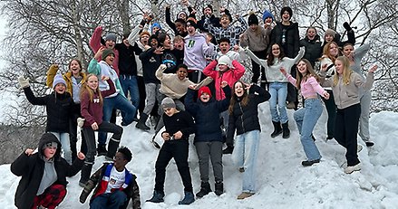 en skolklass med barn som står på en stor snöhög