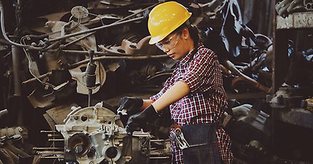 kvinna i gul skyddshjälm som arbetar i industrimiljö