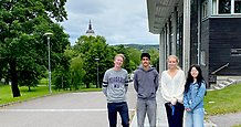Två killar och två tjejer står vid sambiblioteket i Härnösand med stadsparken och domkyrkan i fonden.