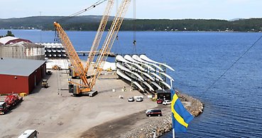 vy över en hamn med en kran och en hög med vindkraftsvingar