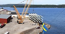 vy över en hamn med en kran och en hög med vindkraftsvingar