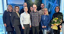 Gruppbild av ett tiotal glada människor på en scen.