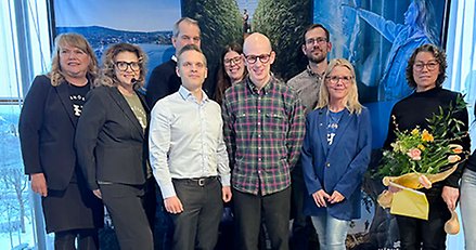 Gruppbild av ett tiotal glada människor på en scen.