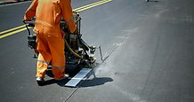 en person i orange kläder jobbar med att måla linjer på en gata