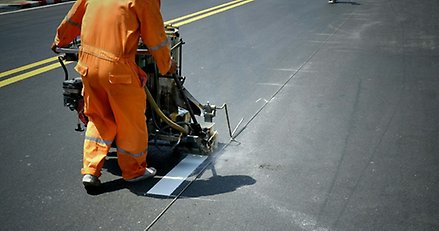 en person i orange kläder jobbar med att måla linjer på en gata