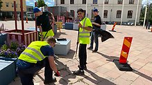 Fyra unga killar som, rensar ogräs på torget.