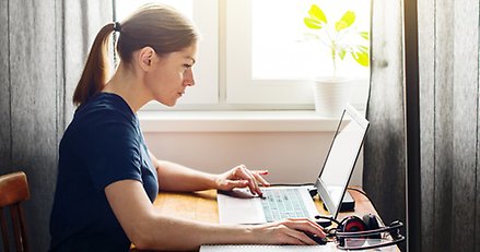 kvinna sitter vid ett bord med en laptop framför sig