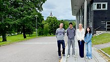 Fyra leende ungdomar vid Sambiblioteket i Härnösand, med stadsparken och domkyrkan i fonden. 