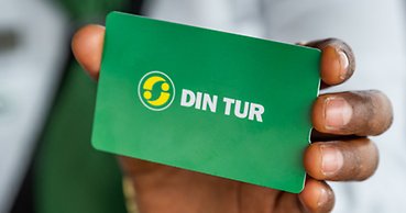 Närbild på en hand som håller fram ett buddkort med texten Din Tur.