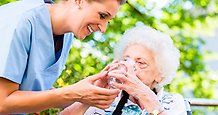 Vårdpersonal hjälper äldre dam att dricka
