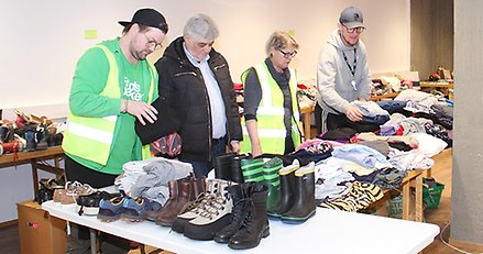 fyra personer vid ett bord fullt med kläder