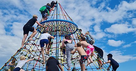 flera barn klättrar uppåt i ett klätternät format som en pyramid