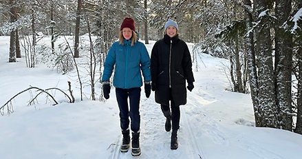 två personer går i skogen på vintern