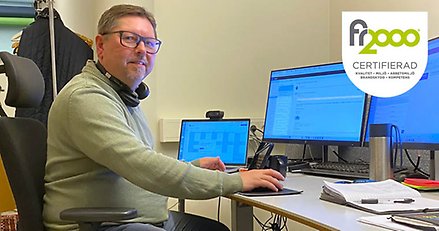 En man arbetar vid ett skrivbord med flera stora datorskärmar.