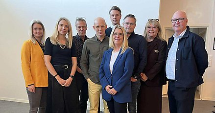 Gruppfoto med nio personer, män och kvinnor i olika åldrar.