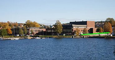 vy över en stor röd byggnad med vatten i förgrunden. intill byggnaden går ett grönt streck