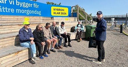 en person står framför en träläktare där det sitter sex personer.