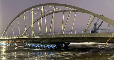 en stor bågbro står på en trailer med många tätt sittande hjul