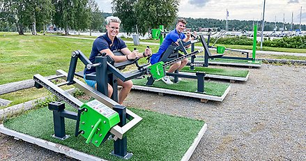 två personer tränaaar vid varsin maskin på ett utegym