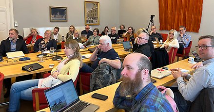 Ett tjugotal personer i ett mötesrum tittar på en talare utanför bild. 