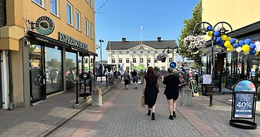 två personer sedda bakifrån är på väg mot ett torg där det finns många människor.