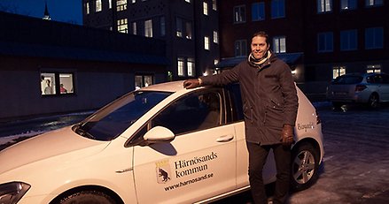 Människa framför bil med Härnösands kommuns logotyp på.