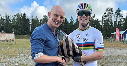 en man lämnar över en blombukett till en man med hjälm på huvudet