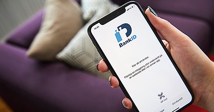 en hand håller i en mobiltelefon där sidan för bank-id är öppen
