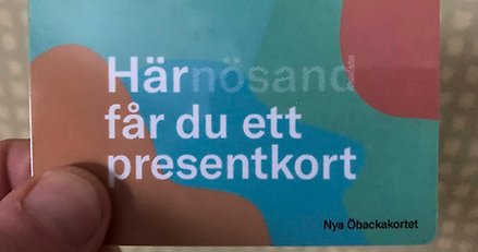 en hand som håller i ett plastkort där det står här får du ett presentkort