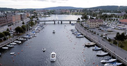 flygbild över ett sund i en stadsmiljö. över sundet går en bro och längs kajerna och i sundet ligger och åker båtar.