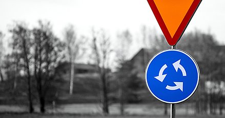 En vägskylt som visar att det är en rondell plus en skylt för att lämna företräde. 