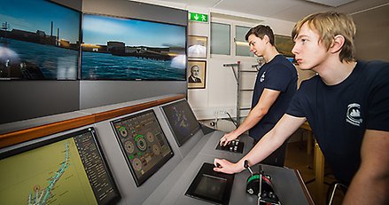 Två unga män arbetar vid en fartygssimulator.