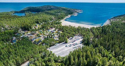 Flygbild över Smitingen och Klubbsjön där man ser stranden, klubbsjön, havet och parkeringen.