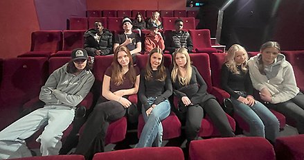 Drygt tio högstadieelever sitter i en biosalong med vinröda fåtöljer.