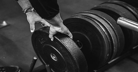 Närbild på två händer som greppar en vikt på ett gym.