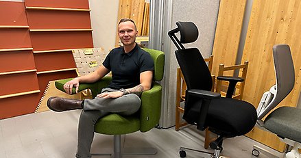 en man sitter i en fåtölj i ett förråd med andra möbler