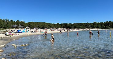 en badstrand med några människor i vattnet och många på stranden