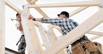 två snickare bygger på en husstomme