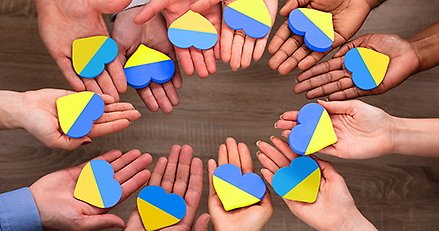 Händer som håller i varsitt hjärta i Ukrainas färger.