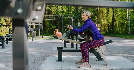 en kvinna använder en maskin på ett utegym