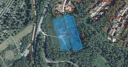 flygbild över ett bostads- och skogsområde med två områden markerade med blått i skogsområdet