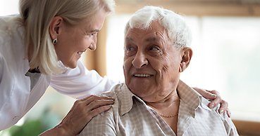 En kvinna som hjälper en äldre man.