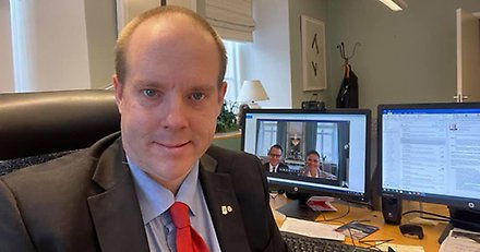 Kommunalråd Andreas Sjölander sitter framför en datorskärm. På skärmen syns kronprinsessparet.