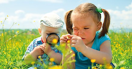 En flicka och en pojke som studerar blommor.