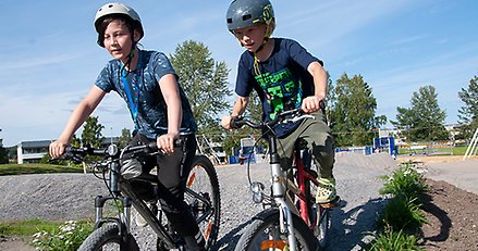 Två pojkar cyklar bredvid varandra