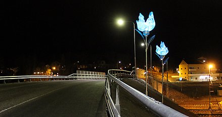 lysande stora konstblommor som står vid en viadukt över järnvägen