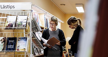 Två människor mellan bokhyllor på ett bibliotek