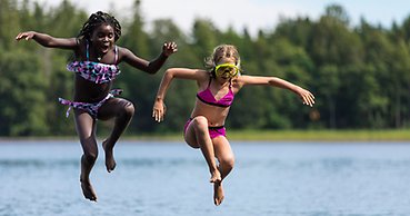 Barn som hoppar i vattnet