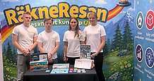 Fyra gymnasister i en monter där de visar upp ett spel. På skynket i montern står ordet "Räkneresan".